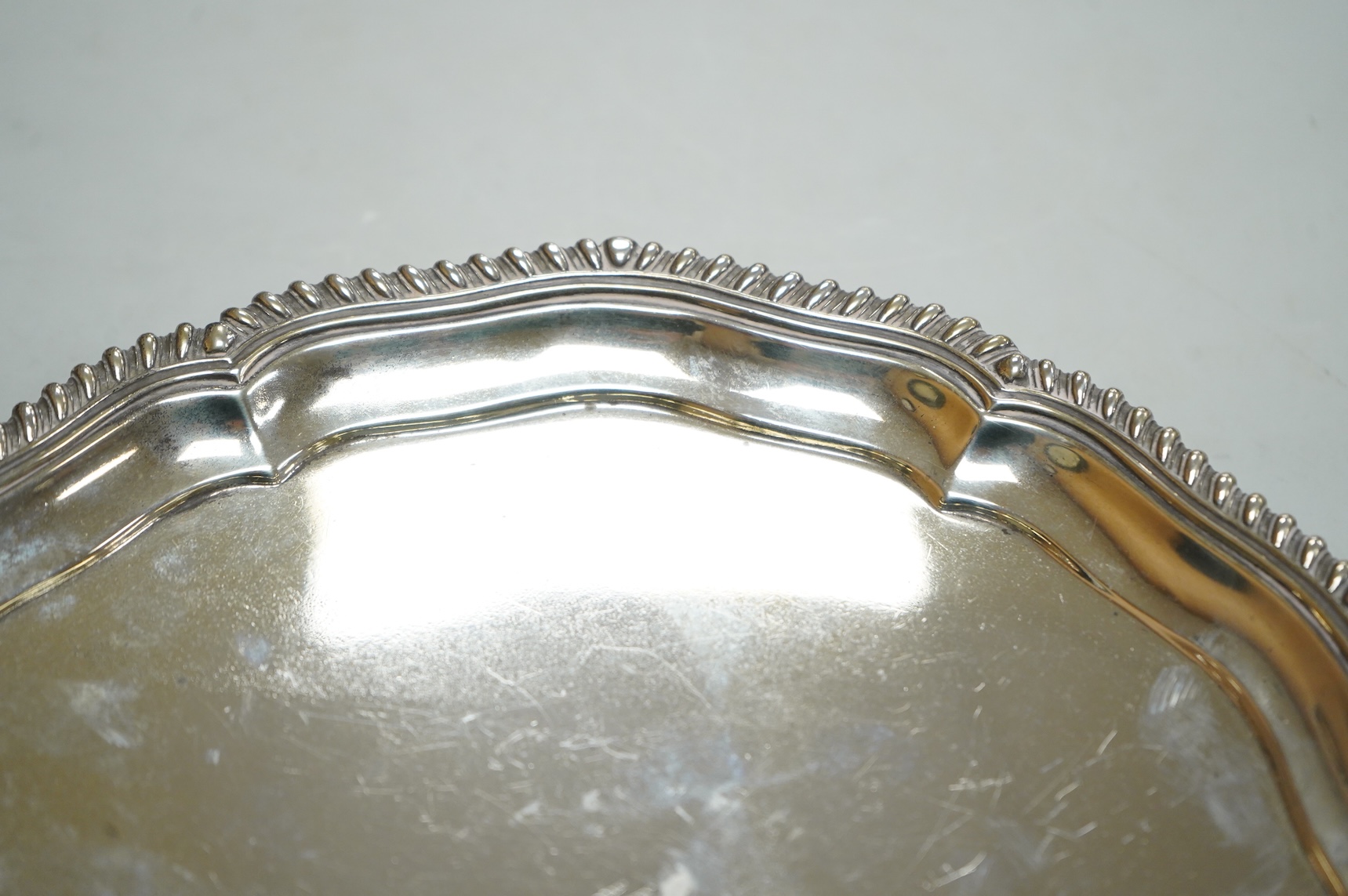 A George V silver salver, by Elkington & Co, of shaped circular form, with engraved crest, on three scroll feet, diameter 26.2cm, 18.7oz.